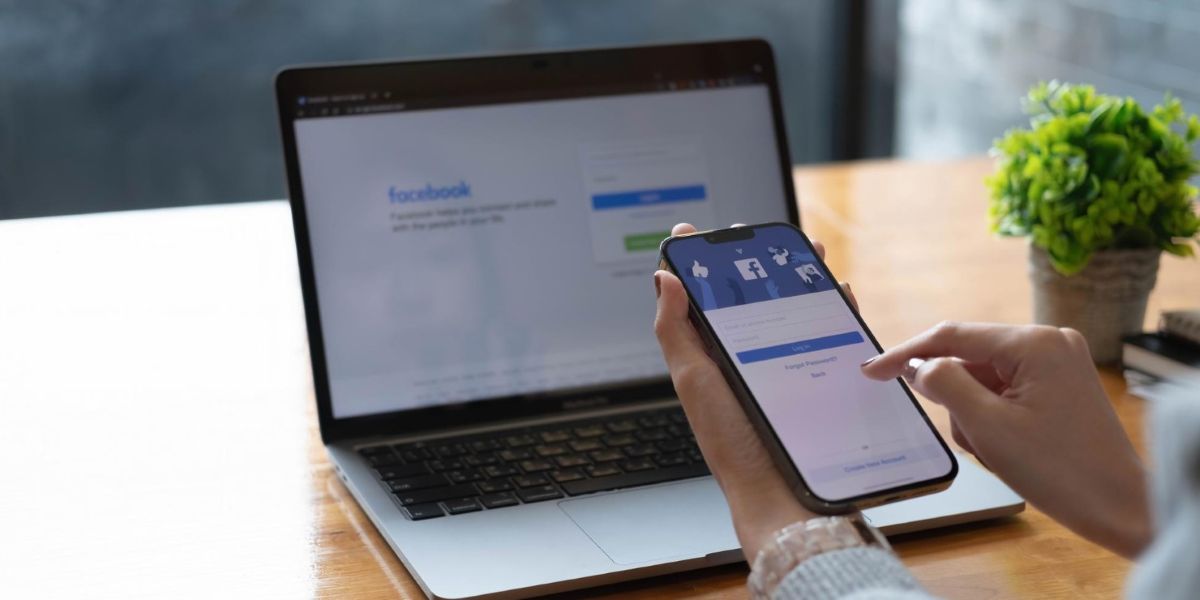 Na pierwszym planie widac smartfona z ekranem logowania do Facebooka, w tle widać laptopa, także z ekranem logowania do Facebooka