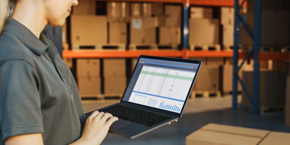 Kobieta w magazynie przeglądająca system do zamówień na laptopie
