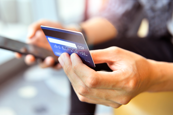 osoba trzyma kartę płatniczą i telefon komórkowy 