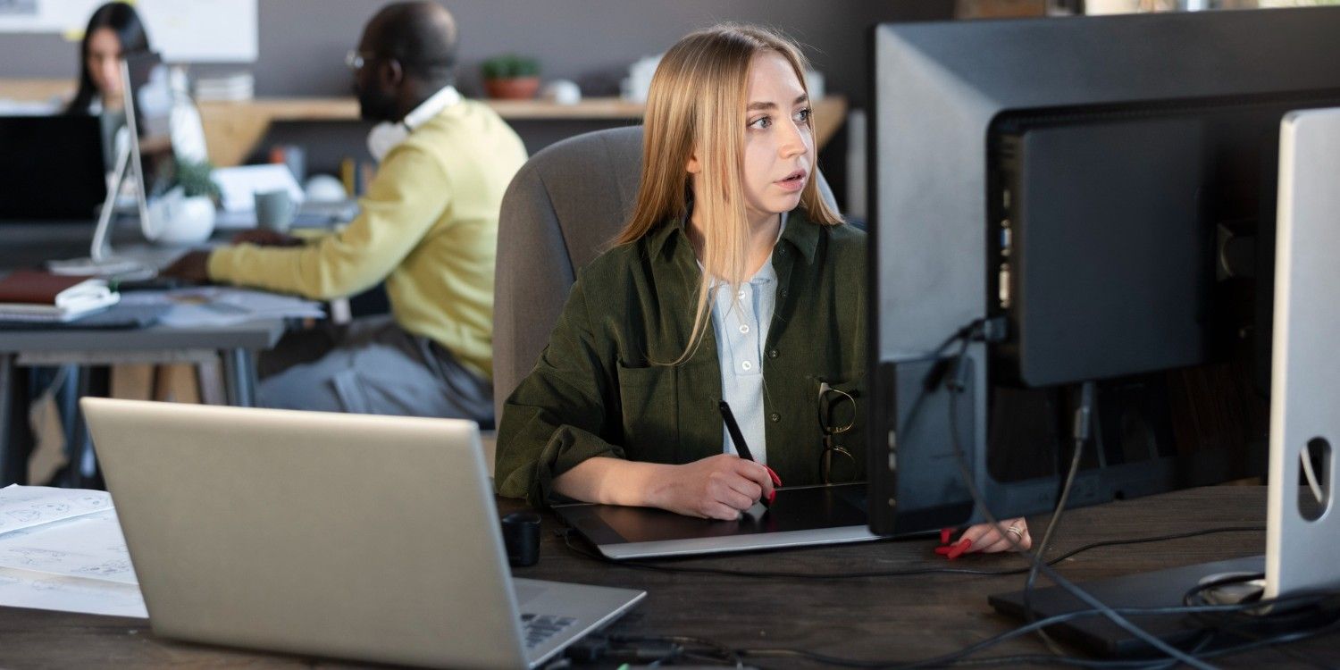 Kobieta korzystająca z komputera na open space, patrzy na cos na monitorze